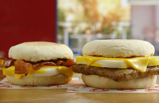 Two Wendy's English Muffin Sandwiches featuring Bacon or Sausage stacked with egg and cheese