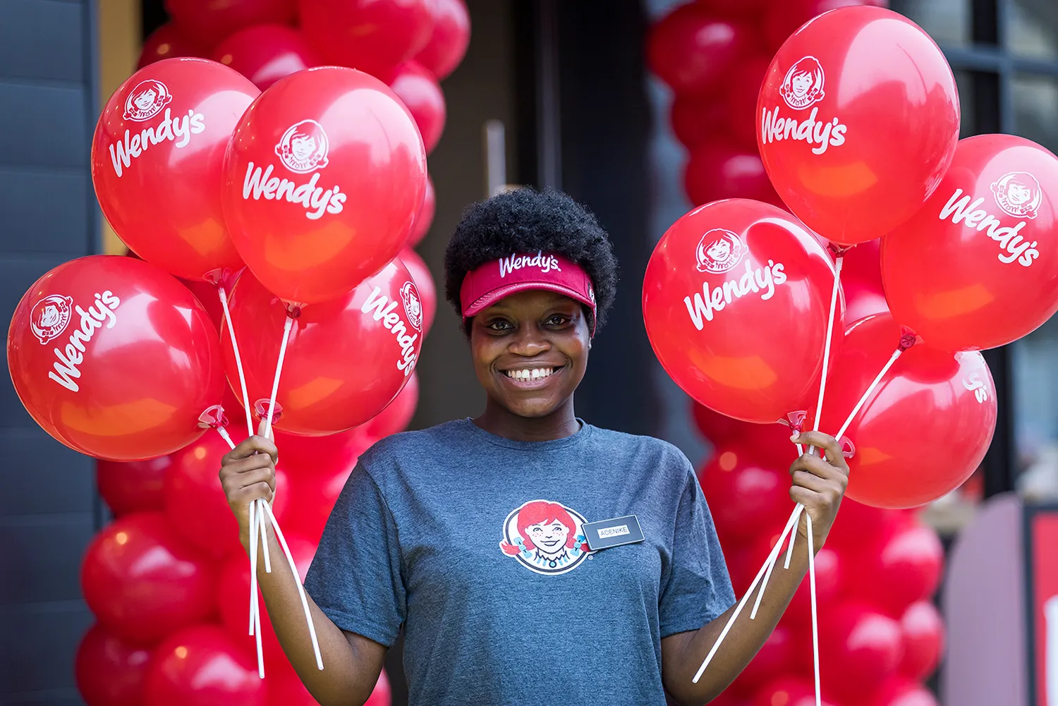Wendy's employee smiling and holding balloons in both hands